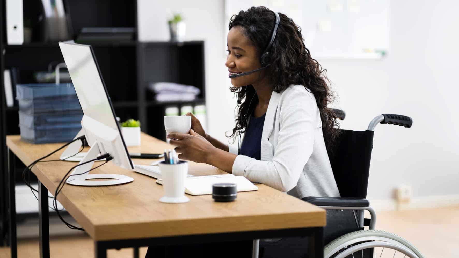 Young woman in a wheelchair sitting at a computer desk at work