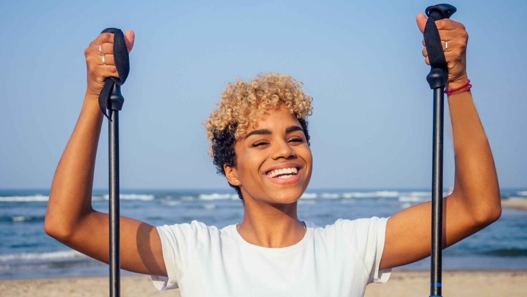 Woman smiling with walking sticks on beach