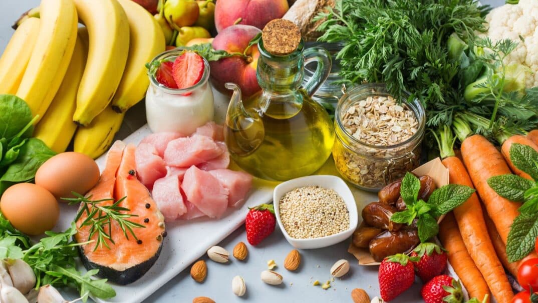 Spread of food on a table. Oils, oats, raw meats, and fruits are pictured.