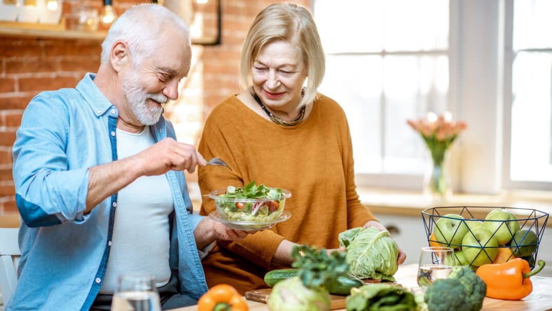 Couple chopping veggies and prepping a salad