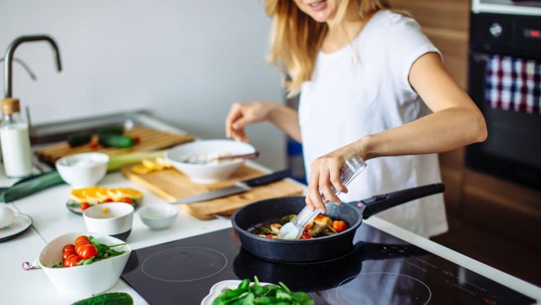Woman Cooking Vegetables on Stove in Kitchen