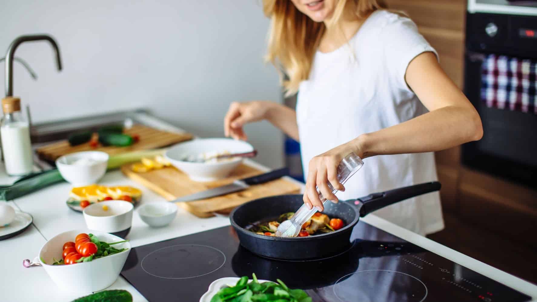 Woman Cooking Vegetables on Stove in Kitchen