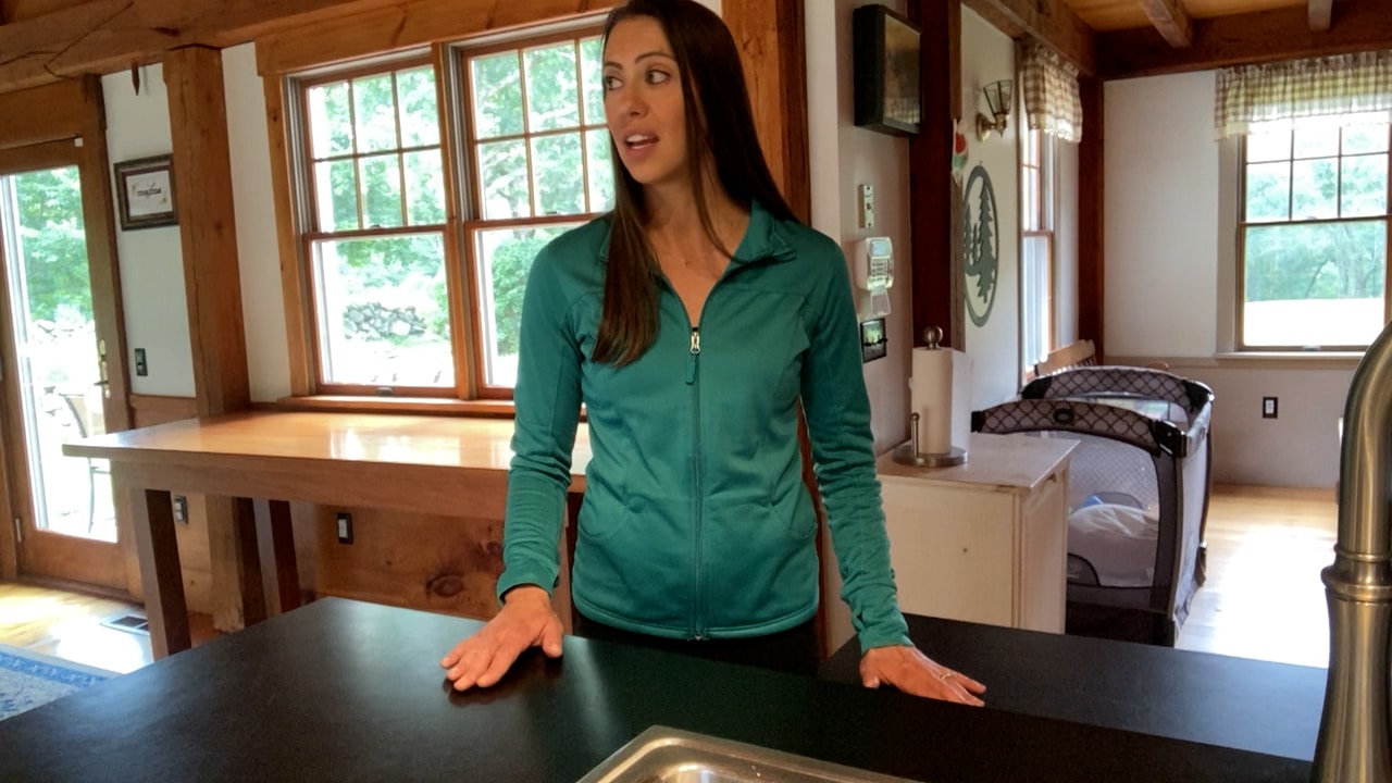 Physical therapist stands at counter to demonstrate exercise to manage dizziness