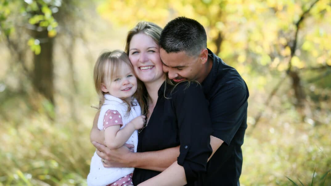 Mother, father, and young toddler embrace in a family hug