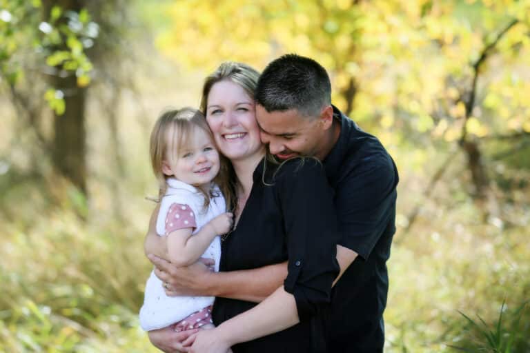 Mother, father, and young toddler embrace in a family hug