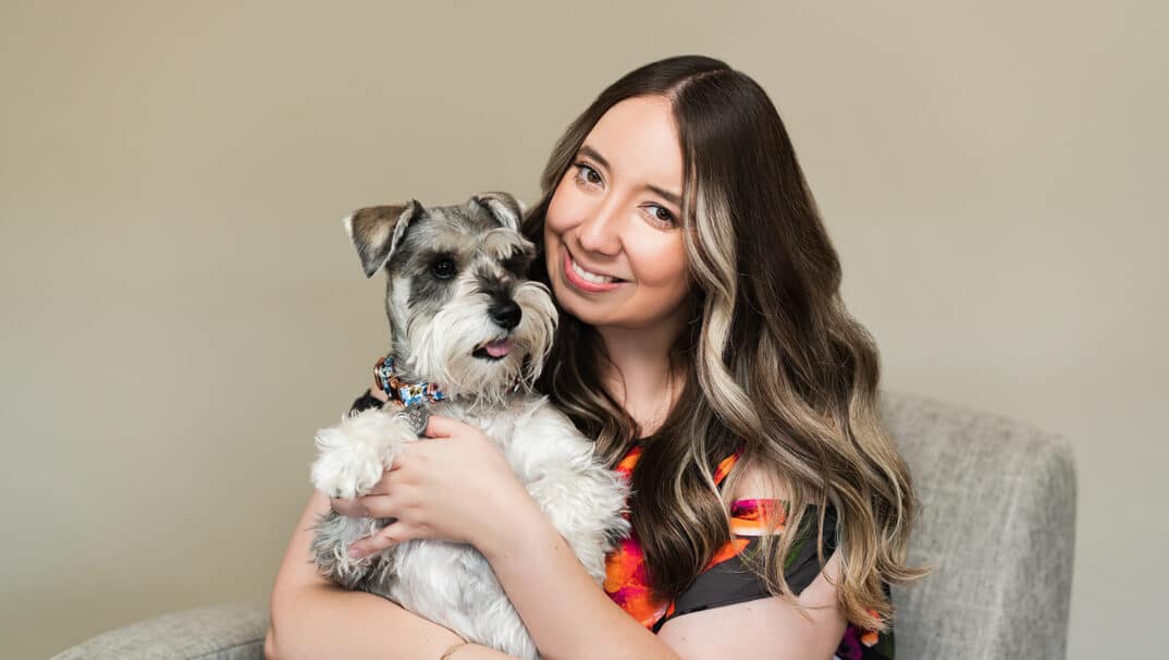 Young adult woman smiles with her schnauzer dog