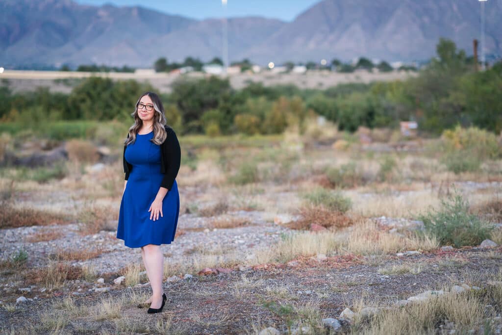 Woman in a blue dress looking directly at the camera, appears wise and empathetic
