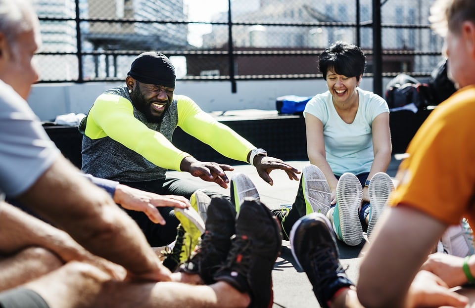 laughing people sit in a circle and stretch together