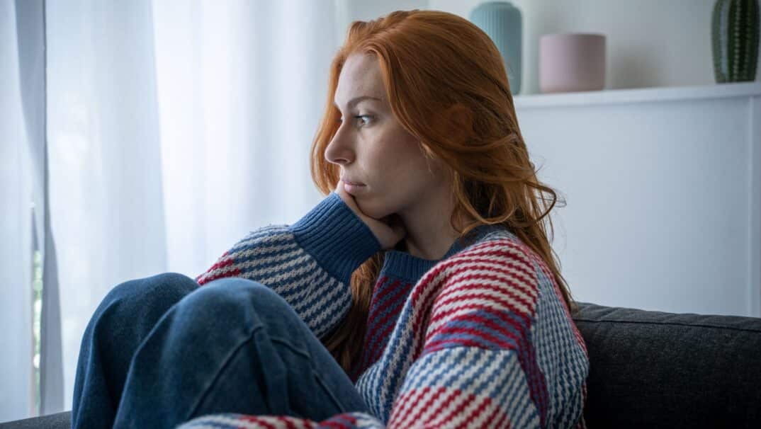 young woman starting out a window blankly