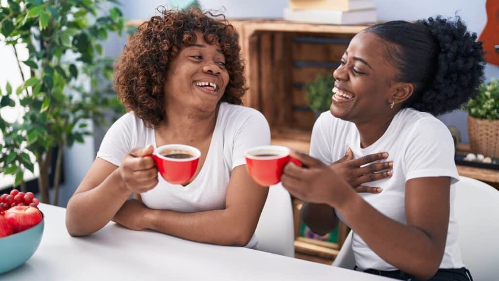 two women laughing and drinking coffee
