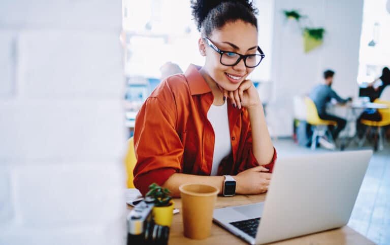 Woman in glasses looking at her computer at a desk