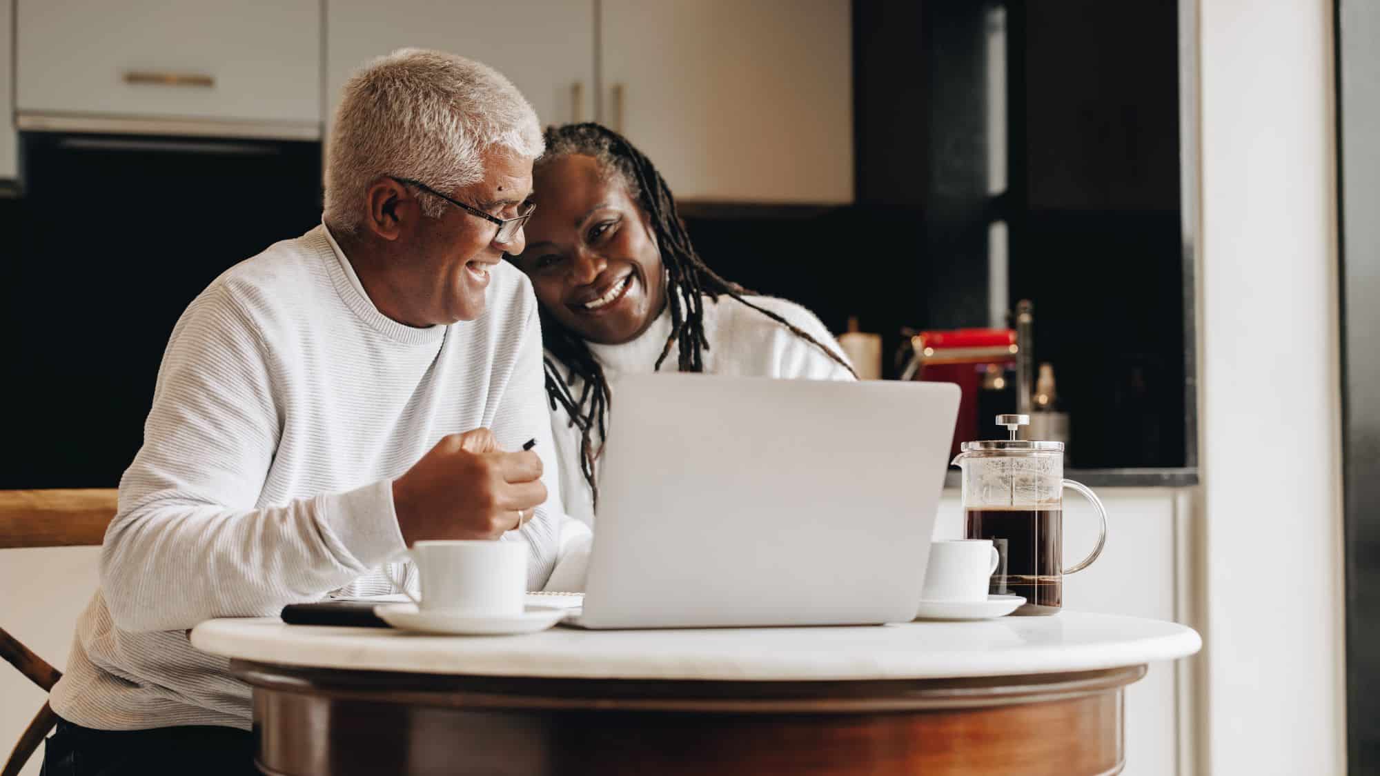 Man and woman sitting in front of a computer laughing