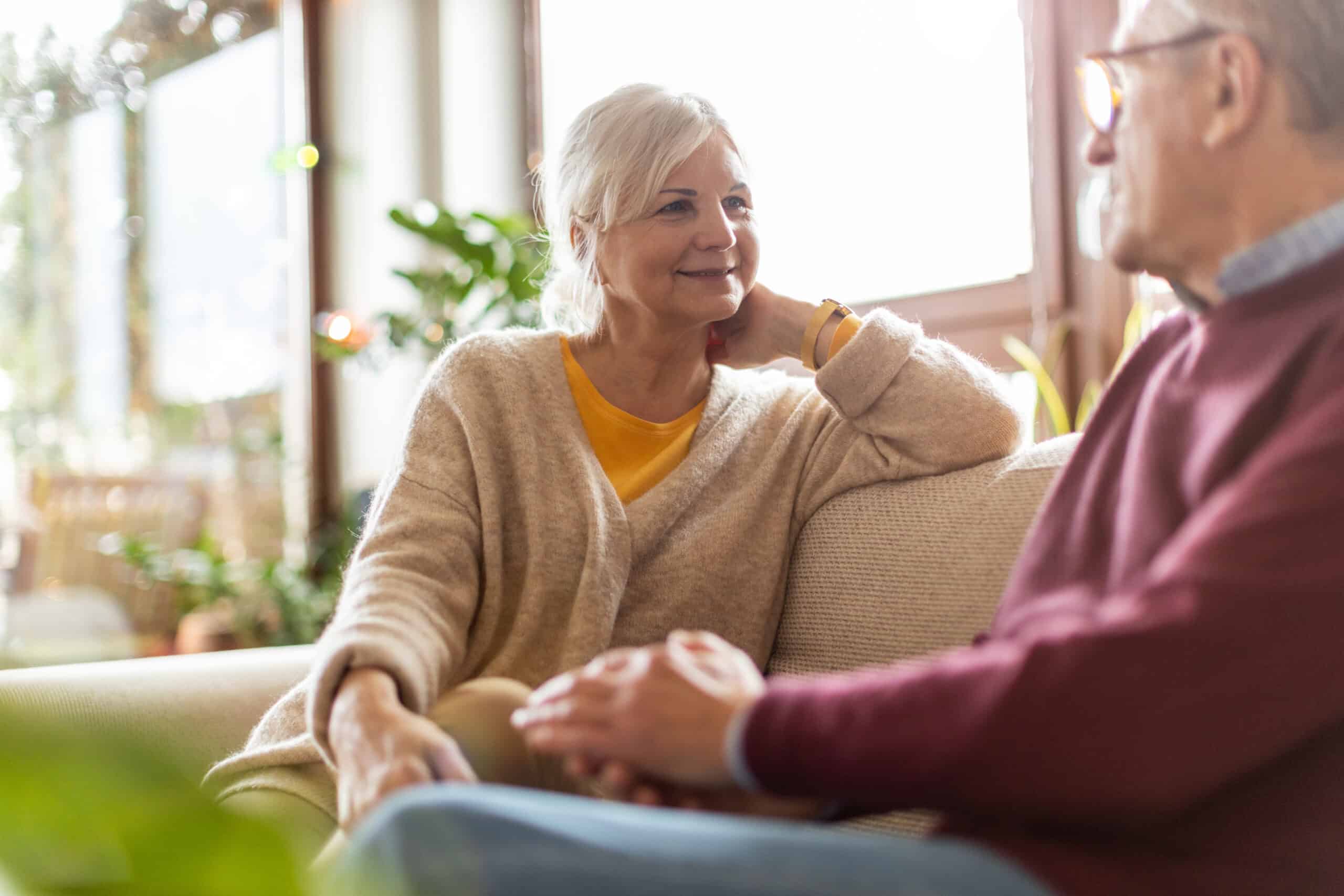 Older white couple sitting on a couch nect to one another
