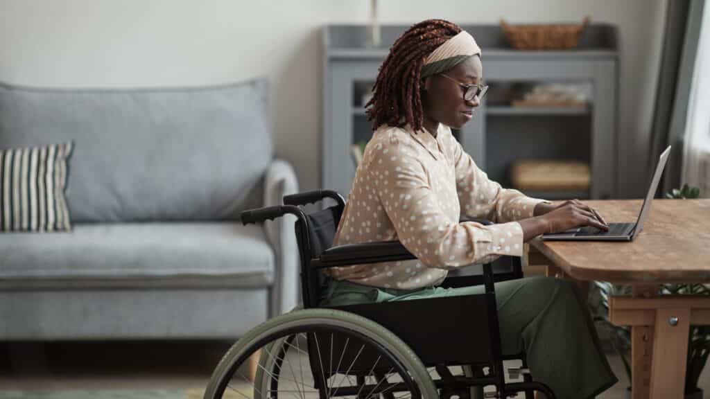 Woman in a wheelchair sitting on a laptop at a desk