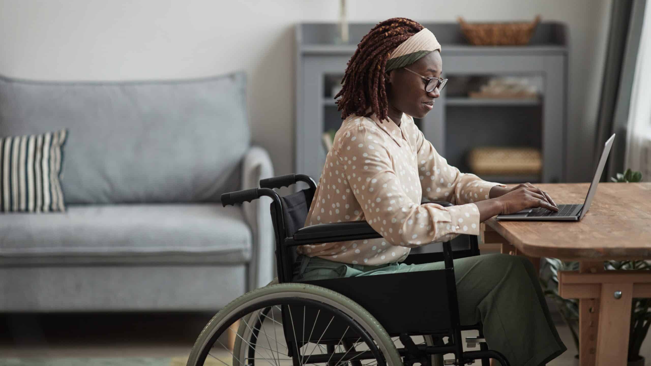 Woman in a wheelchair sitting on a laptop at a desk