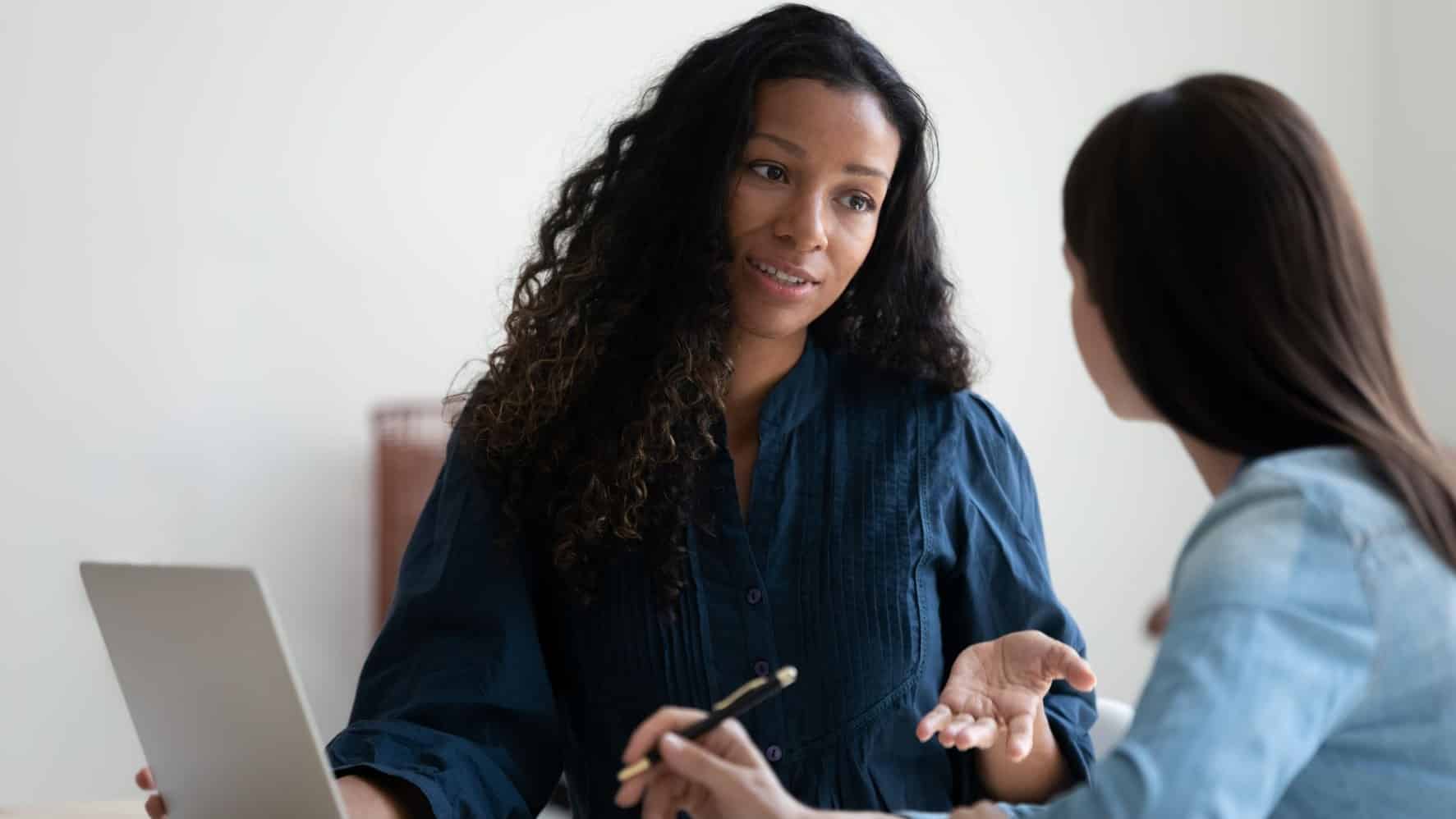 Two female colleagues talking at work