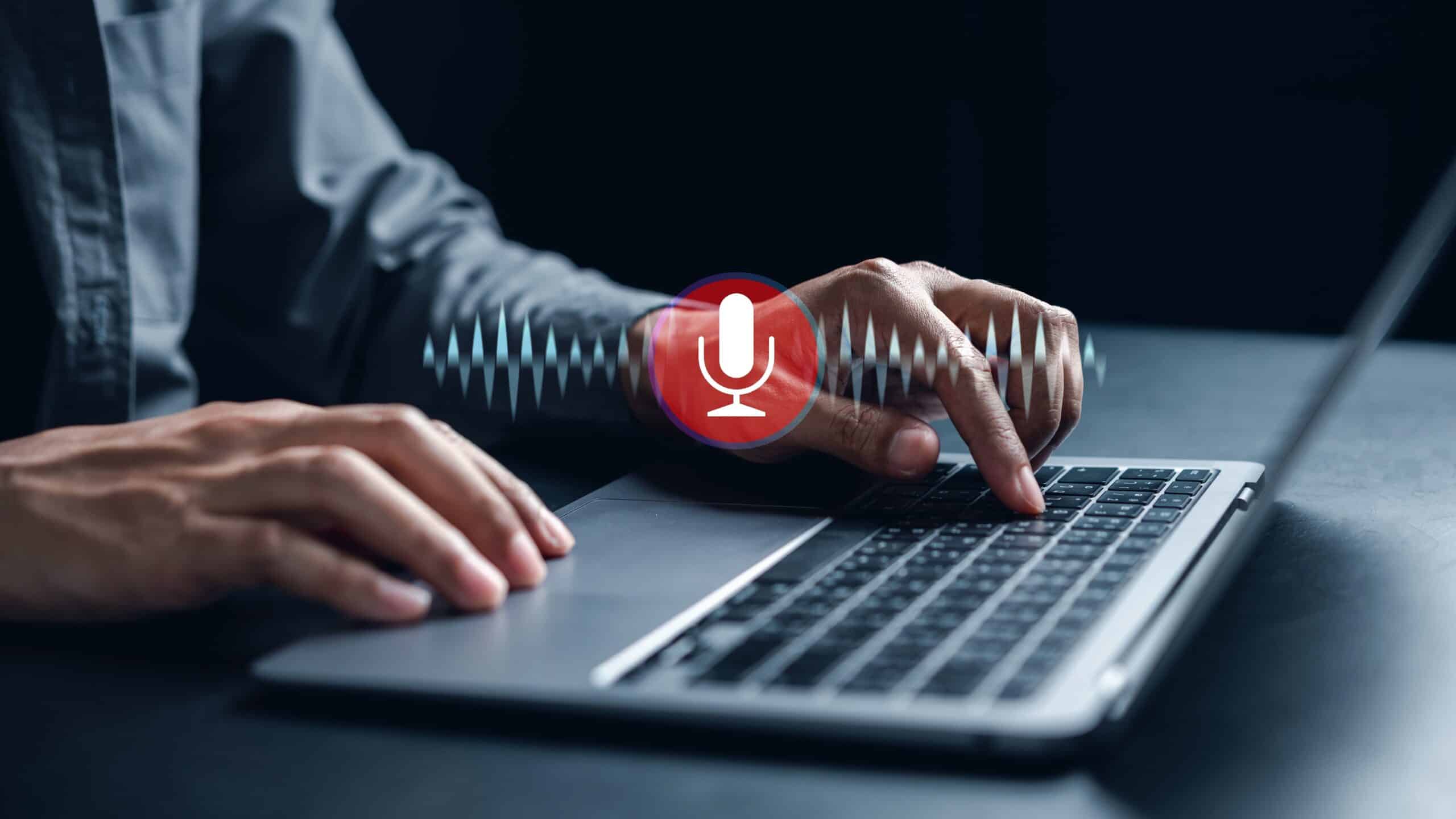 A person using a computer with a speech button and audio waves to detect voice.