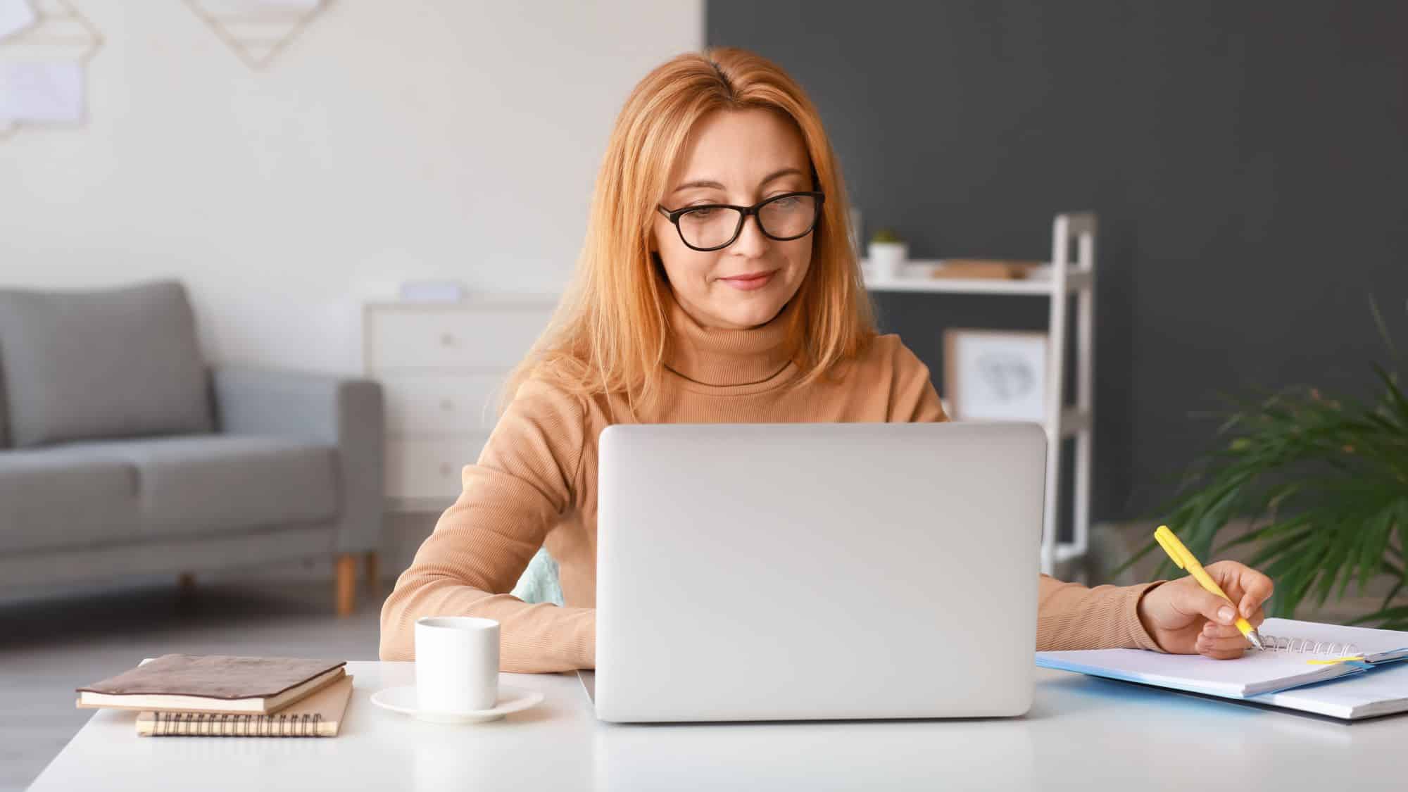 Woman on computer and writing on notebook