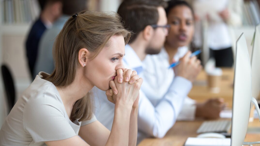 women working with MS frustrated thinking at desk with co workers