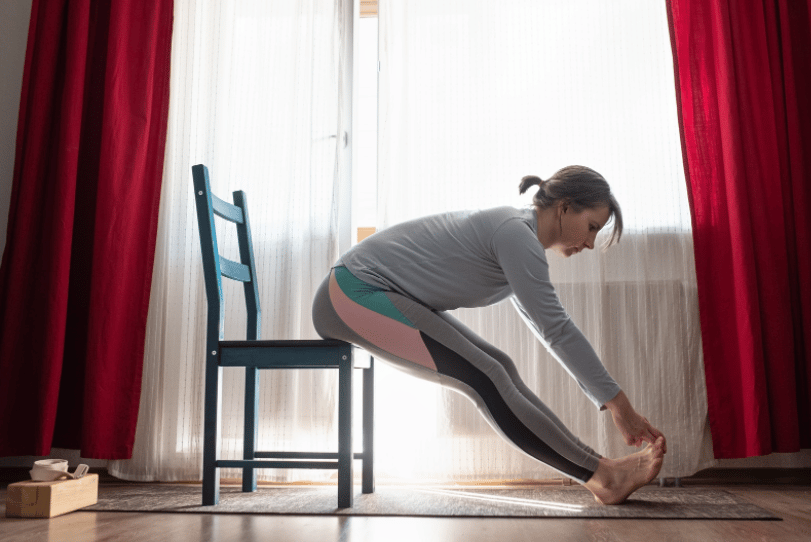 Woman in a chair stretches forward, reaching toward toes, doing a stretching exercise for ms